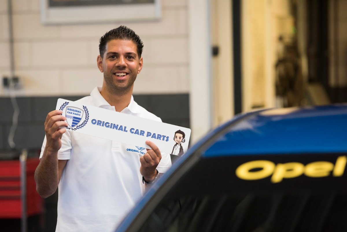 Omar Saadi, owner of Original Car Parts, holding an Original Car Parts licence plate